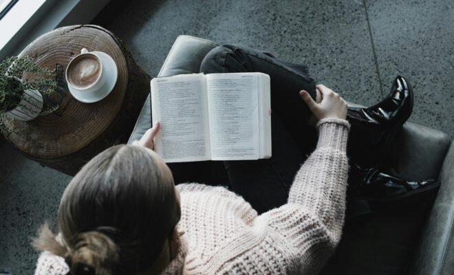 A lady sitting with her legs crossed reading a book