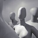 a group of faceless white mannequins standing and facing different ways.