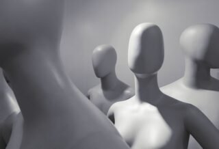 a group of faceless white mannequins standing and facing different ways.