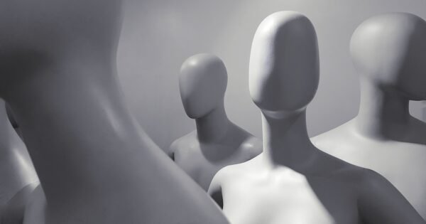 a group of faceless white mannequins standing and facing different ways.
