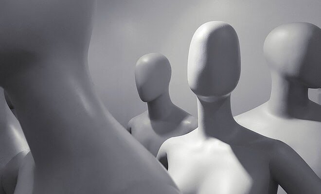 a group of faceless white mannequins standing and facing different ways.