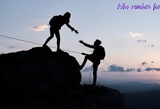 Two silhouettes reach the top of a mountain, backed by the soft light of the setting sun