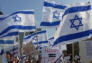 Israel flags being held by people with Hamas protest signs