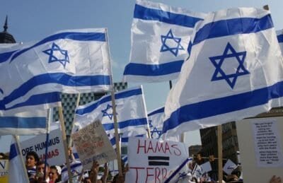 Israel flags being held by people with Hamas protest signs