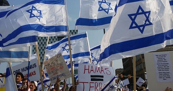 Israel flags being held by people with Hamas protest signs