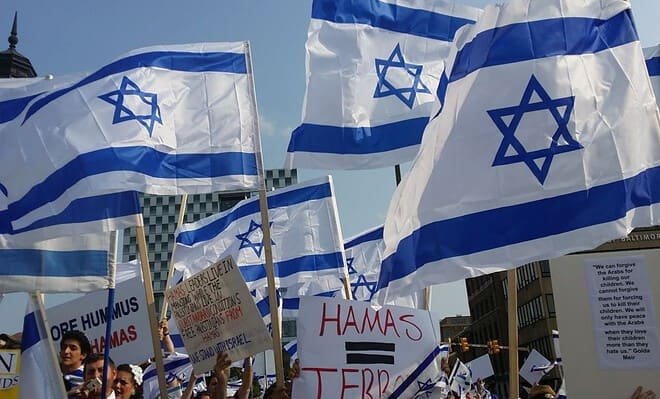 Israel flags being held by people with Hamas protest signs