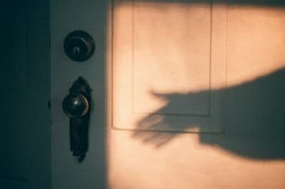 A shadowy hand reaching for an antique doorknob.