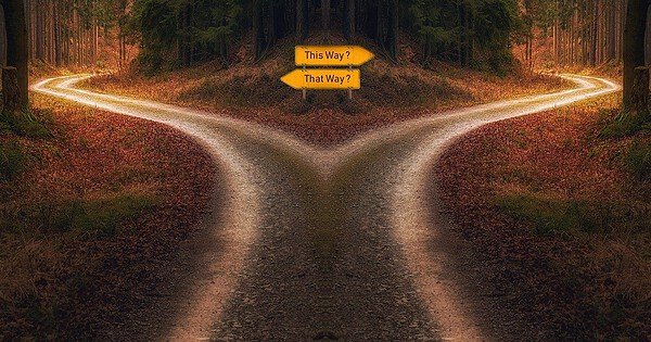 A crossroad with opposing signs in a wooded area