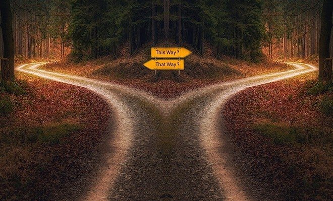 A crossroad with opposing signs in a wooded area