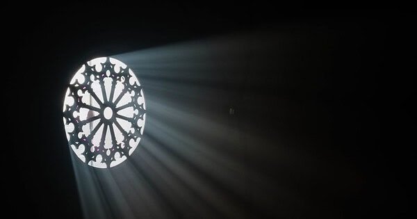 Light shining through a circular window into a dark room.