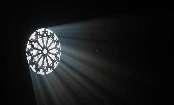 Light shining through a circular window into a dark room.
