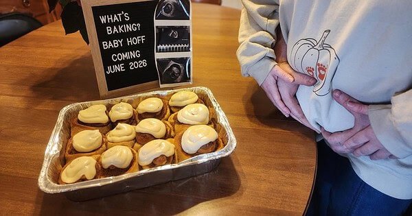 Pregnancy announcement showing a batch of cinnamon rolls with a couple holding her pregnant belly