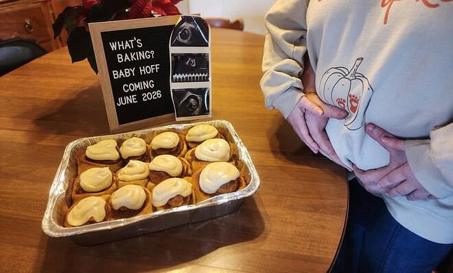 Pregnancy announcement showing a batch of cinnamon rolls with a couple holding her pregnant belly